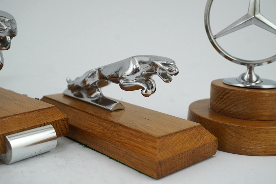 Four car mascots including; a 1920s Alvis eagle mascot designed by Charles Paillet, a Mercedes-Benz mascot, and two Jaguar mascots of different sizes, all mounted on oak bases. Condition - fair to good